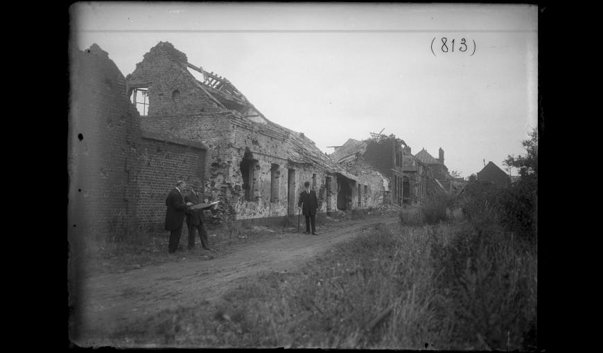 Maisons en ruine, personnage prenant des relevés à Guise