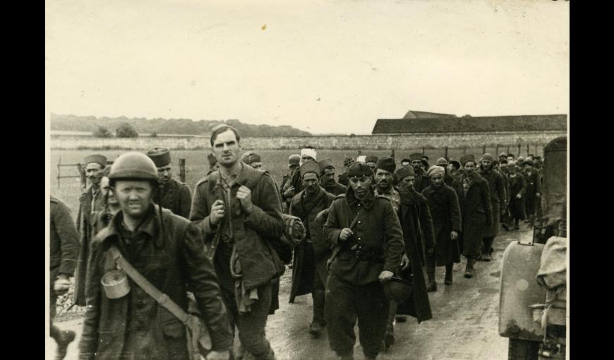 Colonne de prisonniers de guerre français, militaires des troupes motorisés au premier plan et militaires des troupes coloniales au second plan, mai-juin 1940