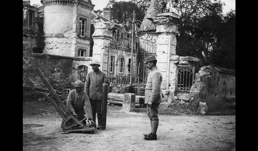Soldats français posant avec un obusier pneumatique Brandt-Lhuillier modèle 1913 de 120 mm devant le Château de Verneuil à Verneuil-Courtonne en parti détruit, 1914-1918