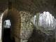 Vue intérieure voûtée des ruines en pierre du fort de la Malmaison, ouvrant sur un sous-bois à l’extérieur.