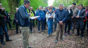 Groupe de participants rassemblés sur un chemin en forêt, écoutant une présentation faite par un intervenant lors de la marche du 16 avril 2026.