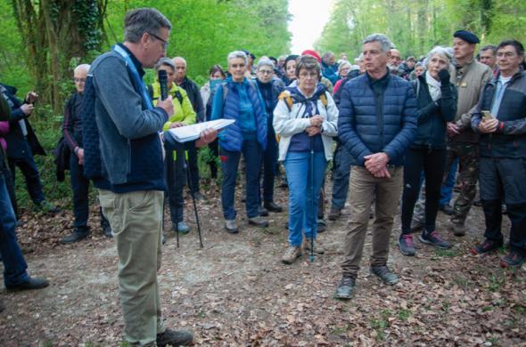 Groupe de participants rassemblés sur un chemin en forêt, écoutant une présentation faite par un intervenant lors de la marche du 16 avril 2026.